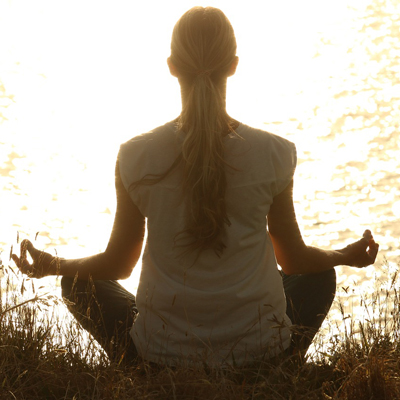 Back view of a woman mediating in the sunlight